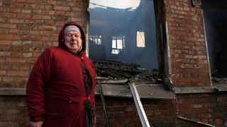 70-летняя Ольга Томах стоит перед жилым домом, в котором сгорела ее квартира после российского обстрела